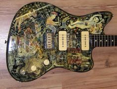 an electric guitar covered in stickers sitting on top of a wooden floor