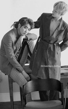 black and white photograph of two people sitting on chairs in front of a desk with a chair