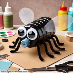 a paper mache insect sitting on top of a table next to craft supplies