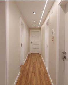 an empty hallway with white walls and wooden floors