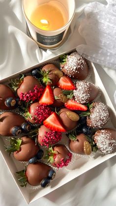 strawberries and chocolate covered strawberries on a plate next to a candle