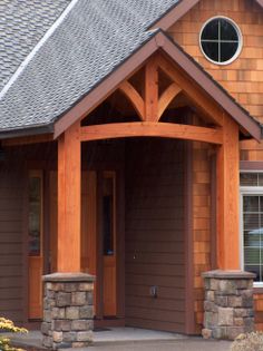 the front entrance to a house with wood trimming and stone pillars on both sides