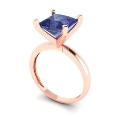 a rose gold ring with a blue sapphire stone in the center, on a white background