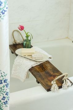 a bathtub with soap and flowers on the edge, next to a towel rack