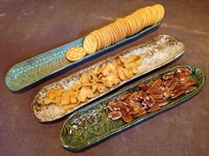 three decorative dishes with corn, chips and crackers on them sitting on a table