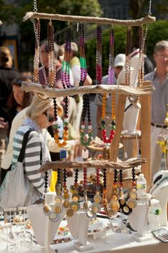 an outdoor market with beads and necklaces hanging from it's display rack on the table