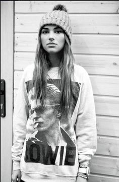 a woman standing in front of a door wearing a hat and sweater with the word love on it