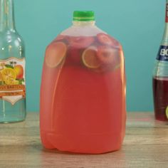 a jug of liquid sitting on top of a wooden table next to bottles of soda