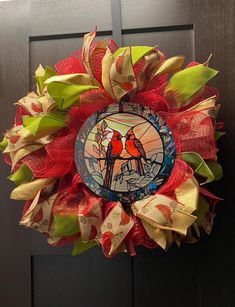 a red and yellow wreath with two birds sitting on top of it, in front of a door