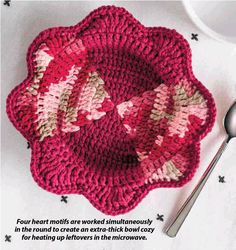 a crocheted dishcloth with pink flowers on it and a spoon next to it