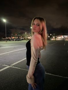 a woman standing in an empty parking lot at night