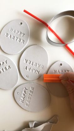 a person is writing on some white tags with red markers and a pair of scissors