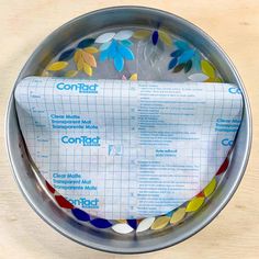 a metal bowl filled with lots of paper and colored confetti on top of it