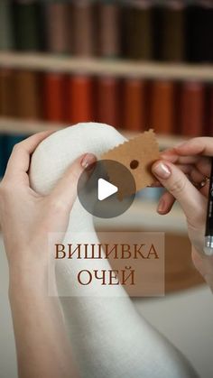 a person is holding a piece of paper in front of a book shelf with books on it