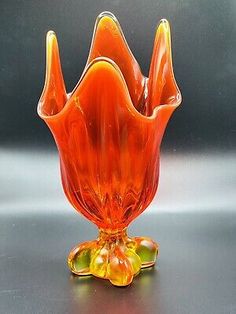 an orange glass vase sitting on top of a table