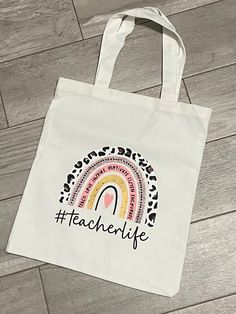 a white tote bag that says teachlife with a rainbow in the middle on it