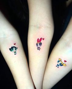 two girls with matching tattoos on their arms, both have small hearts and are holding each other's hands