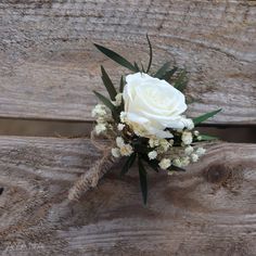 a white rose and baby's breath boutonniere on a wooden bench