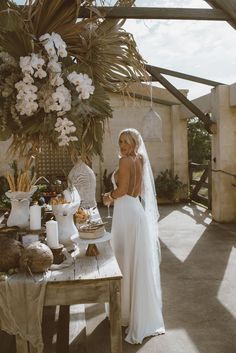 a woman in a wedding dress standing next to a table with food and drinks on it