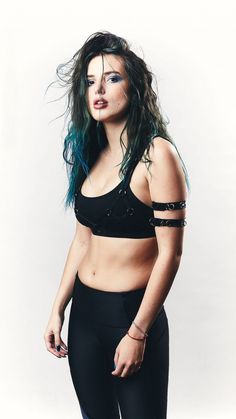 a woman with blue hair and piercings on her chest wearing black sports bra top