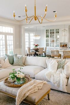 a living room filled with lots of furniture and a chandelier hanging from the ceiling