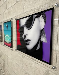 three paintings on the side of a building with sunglasses hanging from it's sides