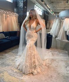 a woman wearing a wedding dress and veil in a bridal room with dresses on display