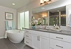 a large white bath tub sitting next to a bathroom sink under a mirror in a bathroom