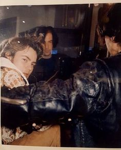 two men in leather jackets and one is holding onto another man's arm with his right hand