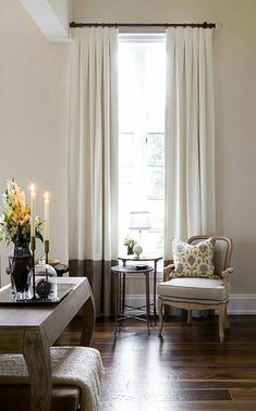 a living room filled with furniture next to a window covered in white curtained drapes