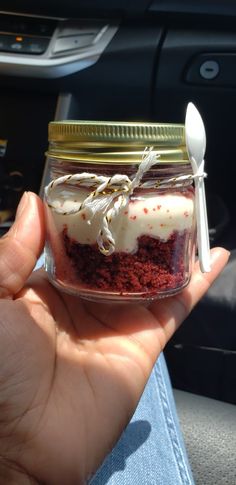 someone is holding up a jar with cake in it