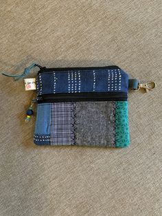 the zippered pouch is made out of several different fabrics and has a key chain attached to it