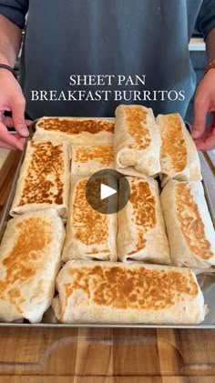 a pan filled with lots of food on top of a wooden table next to a person