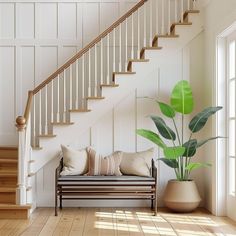 a living room with a couch, plant and stair case in the corner next to it