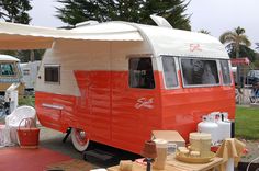 an orange and white camper parked in a parking lot