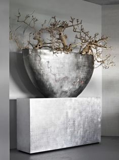 a large metal vase with branches in it