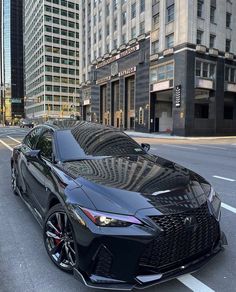 two black sports cars are parked on the street in front of tall buildings and skyscrapers