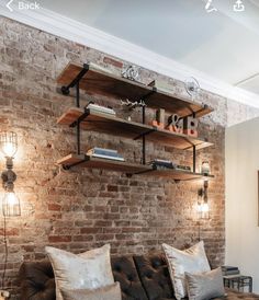 a living room with brick walls and leather furniture in the corner, along with two bookshelves