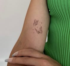 a woman's arm with two small butterflies on the back of her left arm