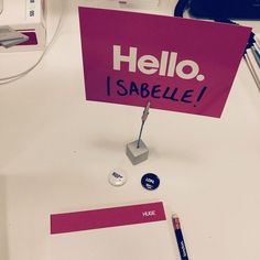 there is a sign that says hello, i sabelle and some pens on the table