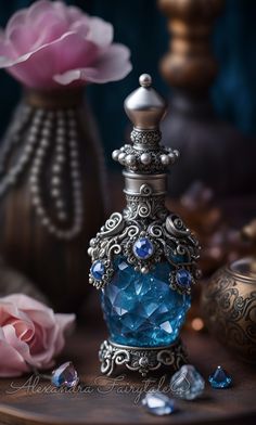 a blue perfume bottle sitting on top of a wooden table next to flowers and pearls