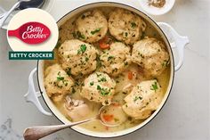 a pot filled with chicken and broccoli covered in gravy next to a spoon