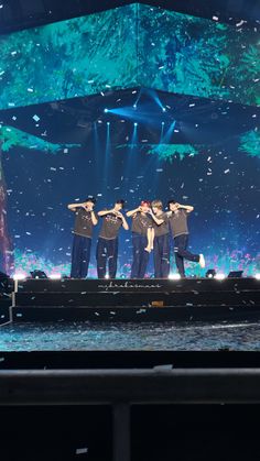 a group of men standing on top of a stage with their arms in the air