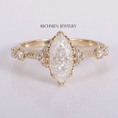 a ring with a pear shaped diamond surrounded by smaller round diamonds on the sides and an oval band