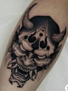 a black and white tattoo on the arm of a person with an evil mask in front of them