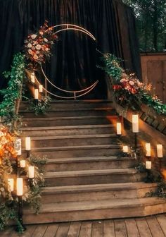 an outdoor ceremony with candles and flowers on the steps leading up to the stage area