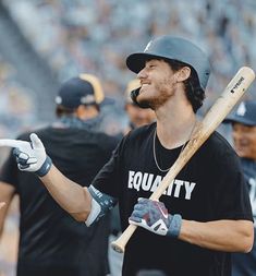 a man holding a baseball bat and wearing a black shirt with the words equality on it