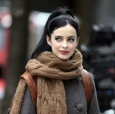 a woman with black hair wearing a brown scarf