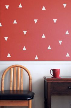 two chairs and a table in front of a red wall with white triangles on it