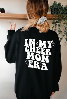 Elevate your cheer mom game with our 'In My Cheer Mom Era' Sweatshirt! Stay cozy and show your pride as you cheer on your star athlete. Perfect for chilly game days and practice sessions. Get yours today and embrace the cheer mom era in style! Experience ultimate comfort in any scenario with our Unisex Heavy Blend Crewneck Sweatshirt. Crafted from a blend of polyester and cotton, these garments not only feel incredibly soft but also ensure your designs stay crisp and vibrant. The ribbed knit col Cheer Mom Aesthetic, Black Long Sleeve Cheerleading Sweatshirt, Black School Spirit Sweatshirt For Cheerleading, Black Sweatshirt For Cheerleading In Fall, Black Tops With Team Spirit Lettering, Cheerleading Letter Print Crew Neck Sweatshirt, Crew Neck Sweatshirt With Letter Print For Cheerleading, Crew Neck Graphic Print Sweatshirt For Cheerleading, Black Top With Letter Print For Cheerleading